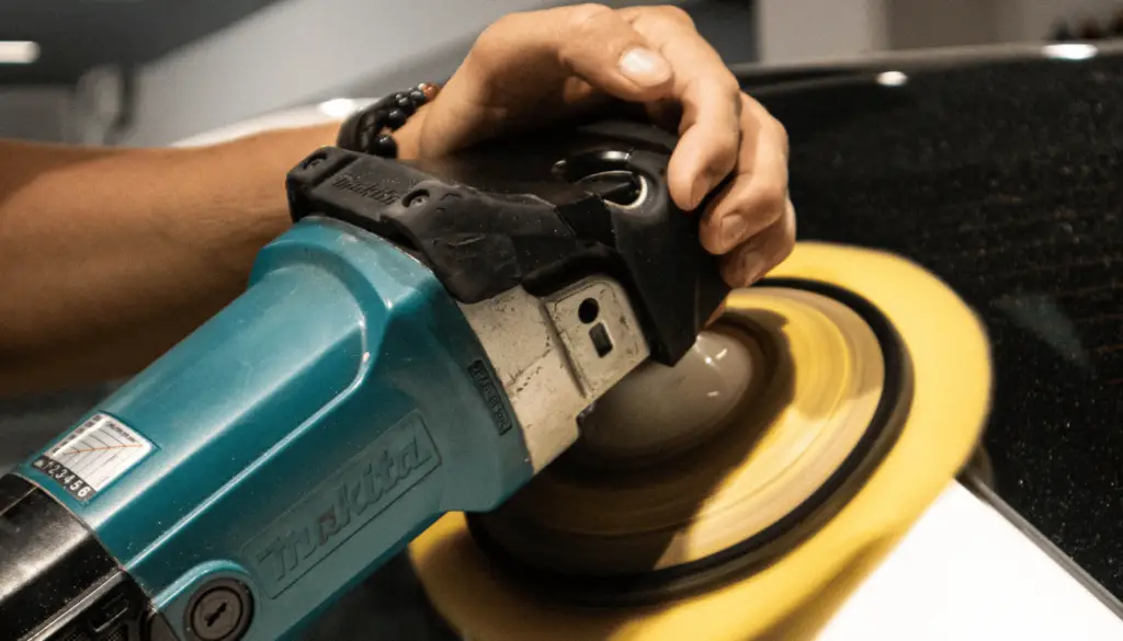 car being treated by a buffing machine to prepare for ceramic coating