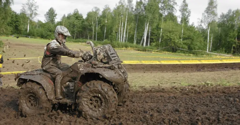 extremely dirty atv in a mud patch that will need to be cleaned later