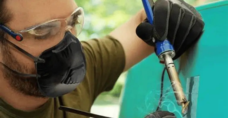 an experienced autobody technician using a saudering iron and plastic to perform heat-based plastic welding