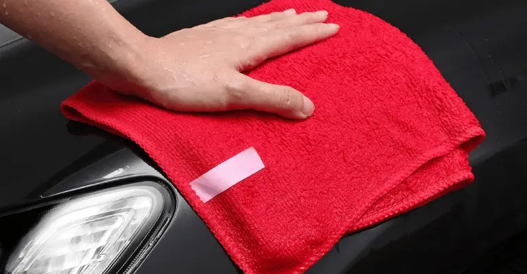 red microfiber towel being used on a black car with a ceramic coating